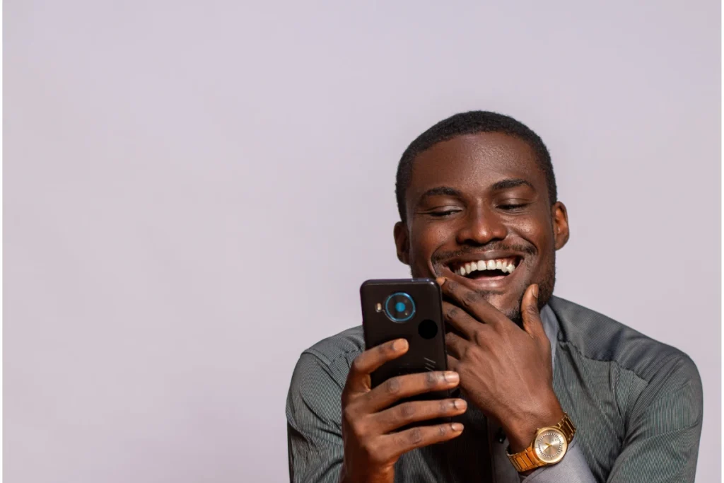Top 5 Budgeting Apps Smiling man looking at his smartphone, enjoying a personal finance or budgeting app