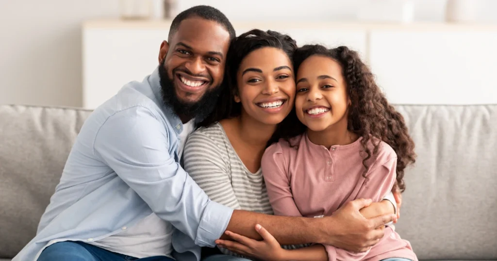 When is a Will Enough appy family of three smiling and sitting on a couch together, representing a simple estate situation where a will may be sufficient
